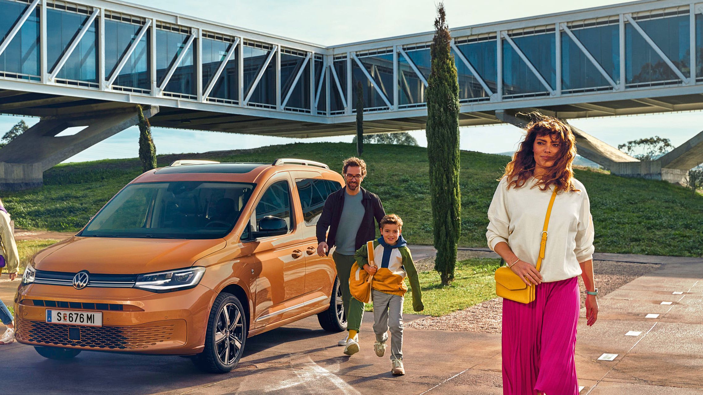 Ein weißer Caddy Kastenwagen mit geöffneter Heckklappe von schräg hinten. Ein Mann lädt gerade Holz ein.