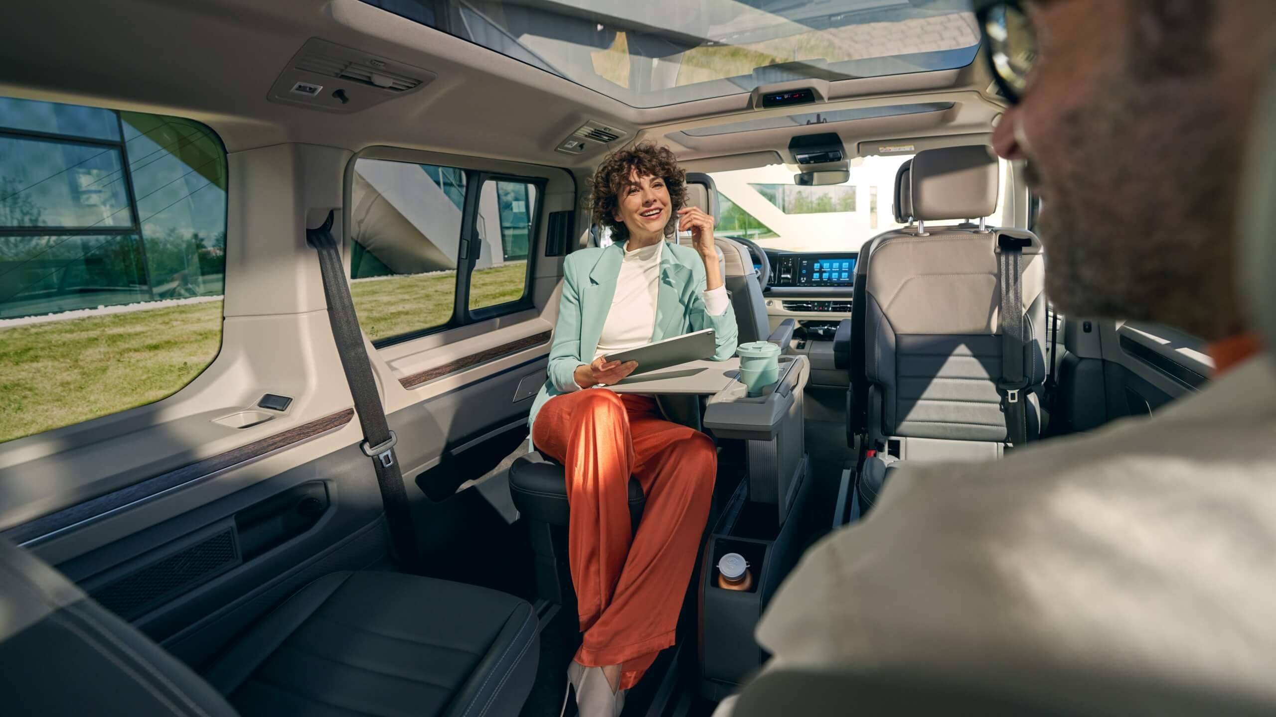 Eine Frau sitzt am Multifunktionstisch des neuen VW Multivan T7 2021. 