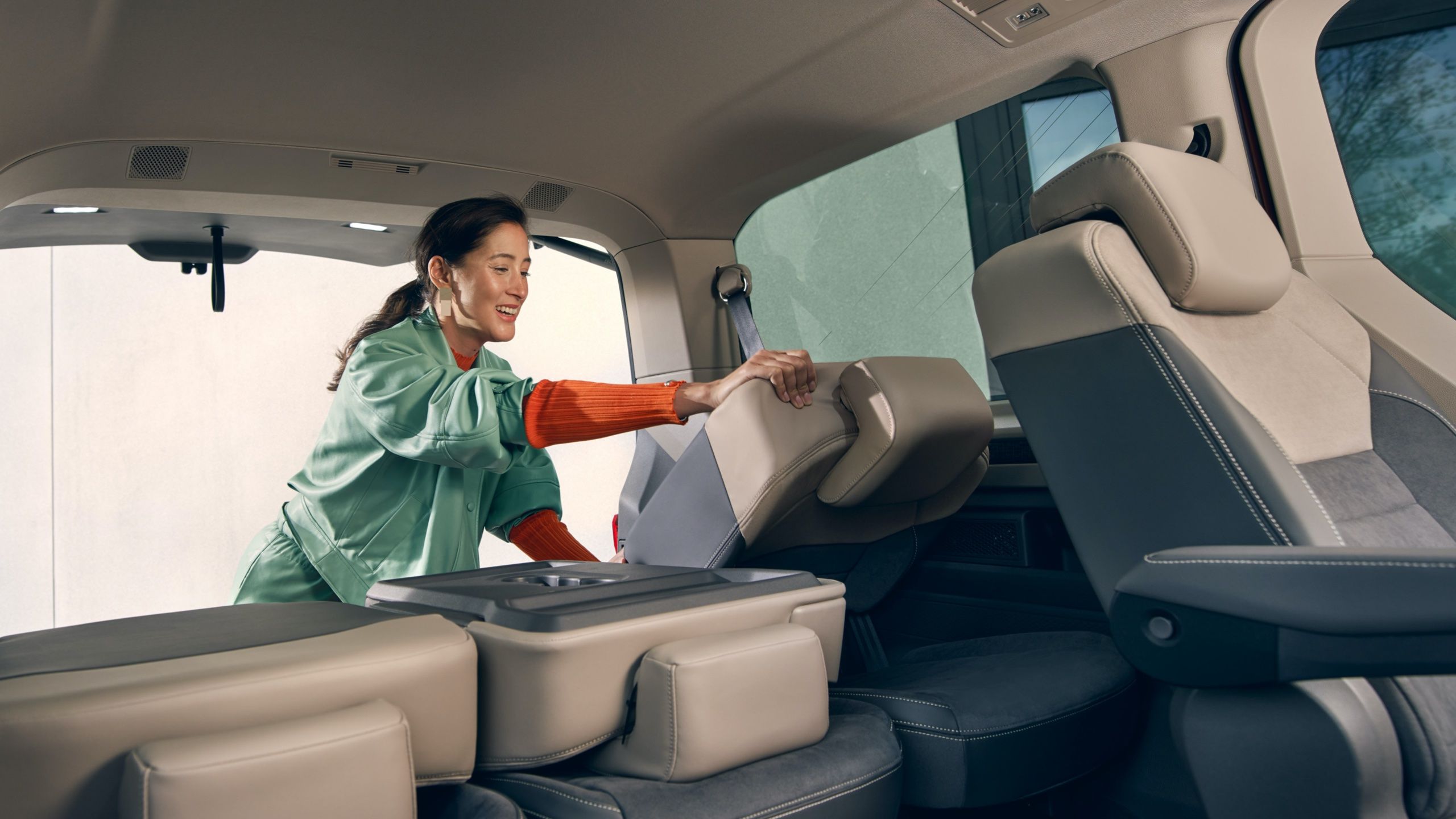 Eine Frau klappt im VW Multivan T7 2021 die Sitze um. 