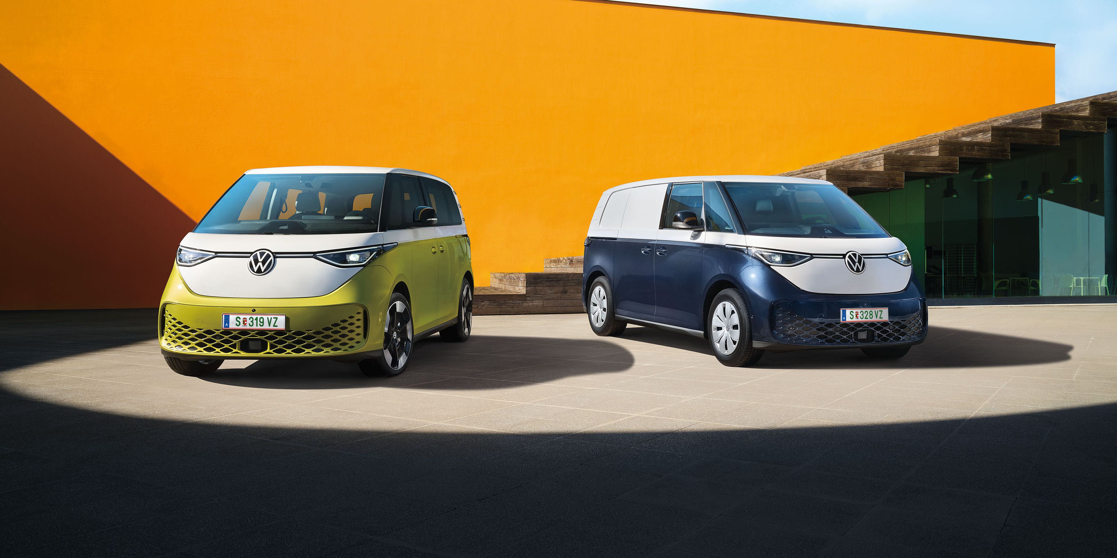 Der VW ID. Buzz in Weiß Gelb und der VW ID. Buzz Cargo in Weiß Blau stehen nebeneinander
