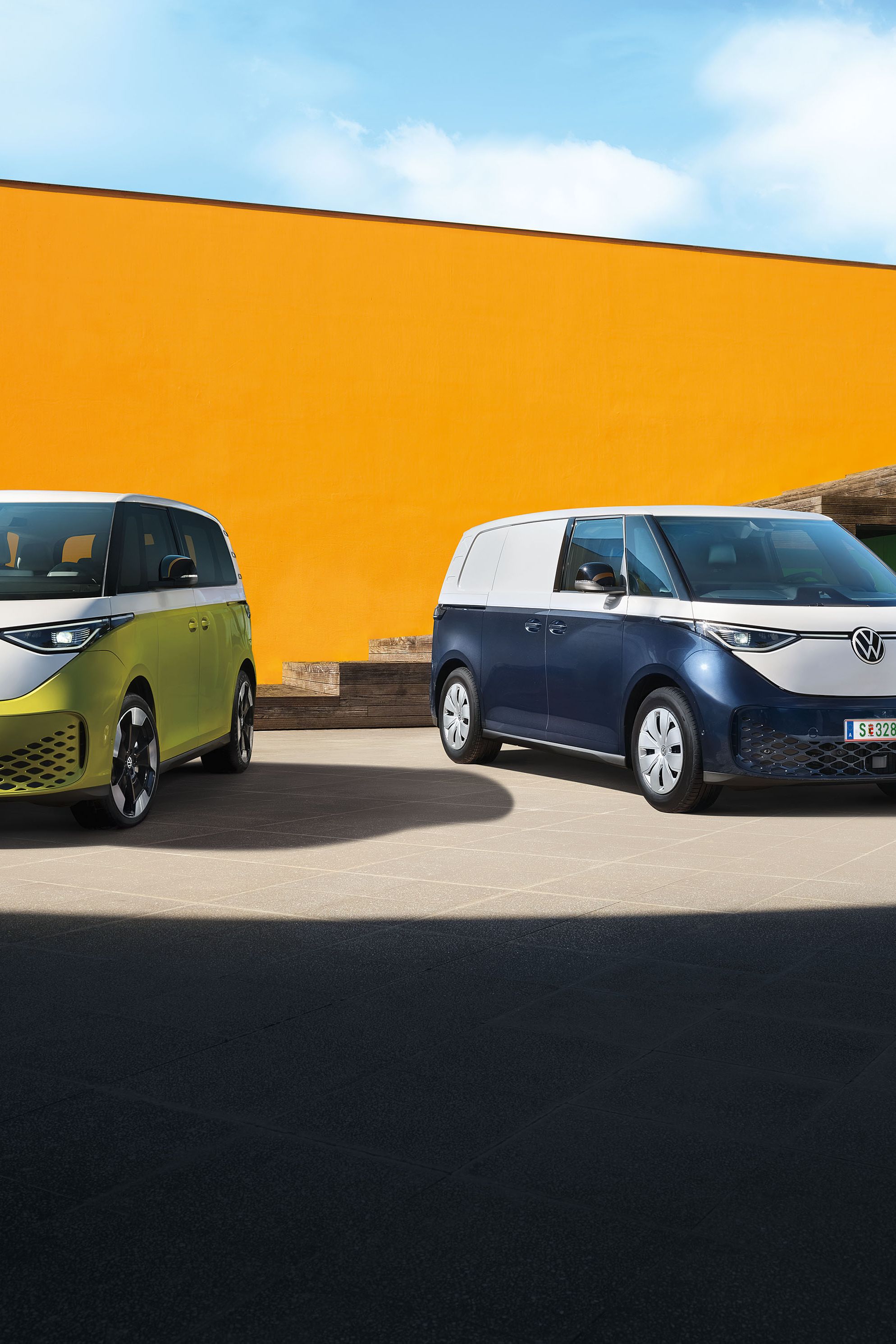 Der VW ID. Buzz in Weiß Gelb und der VW ID. Buzz Cargo in Weiß Blau stehen nebeneinander
